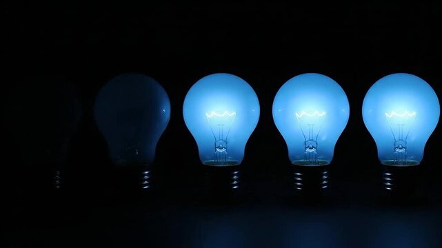 Row of glowing blue light bulbs illuminating a dark background