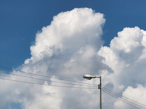 Streetlights against a blue, cloudy sky; streetlight poles are commonly found in urban or rural landscapes for illumination.