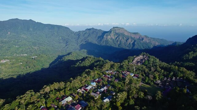 Aerial view of Bena Traditional Village with its iconic thatched roofs nestled among lush green mountains and forests in Kecamatan Jerebuu, Nusa Tenggara Timur, Indonesia.
