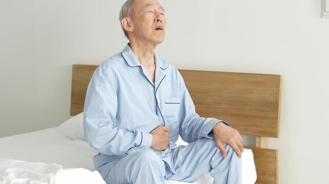 お腹を押さえる体調不良の高齢者の男性
