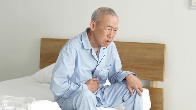 お腹を押さえる体調不良の高齢者の男性