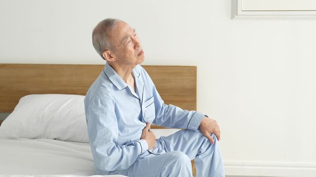 お腹を押さえる体調不良の高齢者の男性
