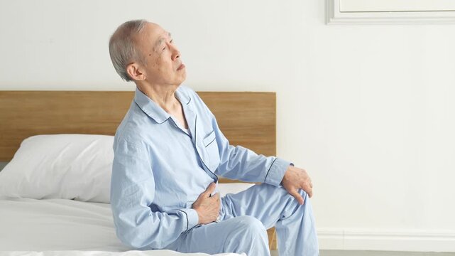 お腹を押さえる体調不良の高齢者の男性