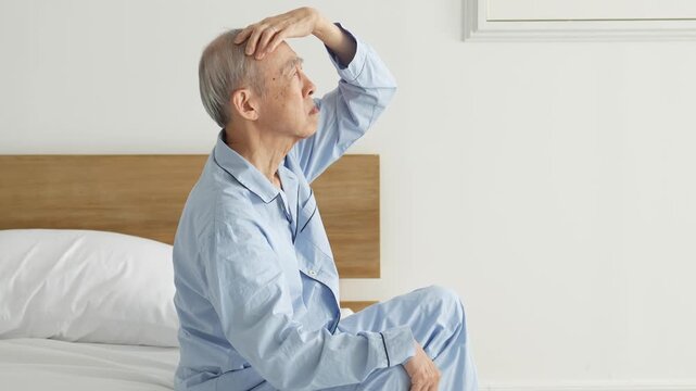 頭を押さえる体調不良の高齢者の男性