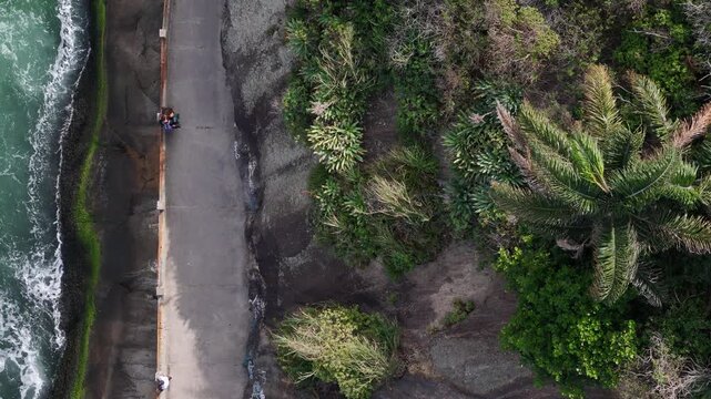Aerial view of Praia do Leme coastal path with waves crashing against the rocks and lush tropical vegetation in Rio de Janeiro, State of Rio de Janeiro, Brazil.
