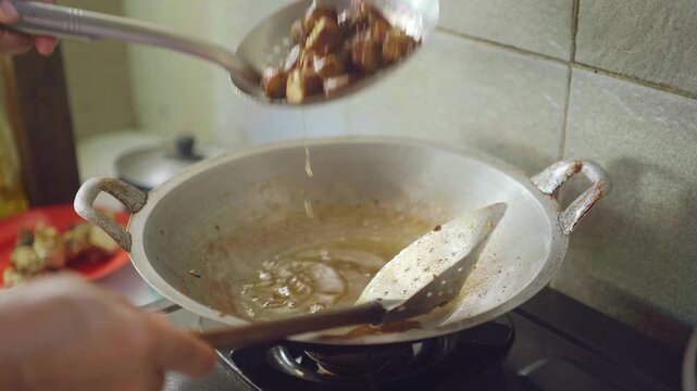 Woman is cooking Urutan, a homemade balinese pork sausage in the pan with hot oil. 4K vertical footage. Culinary concept