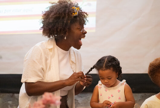 Mother braiding her smiling young daughter's hair, showing family togetherness and care