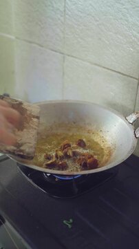Woman is cooking Urutan, a homemade balinese pork sausage in the pan with hot oil. 4K horizontal footage. Culinary concept