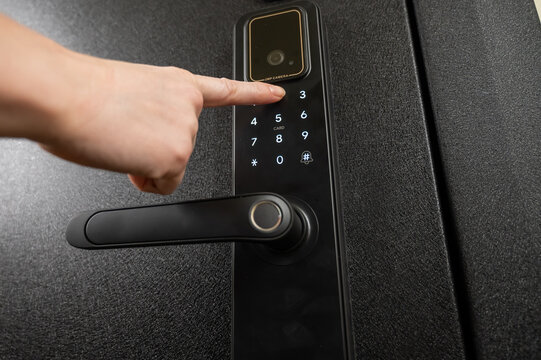 A woman opens a modern smart door lock with a digital keypad using a code.