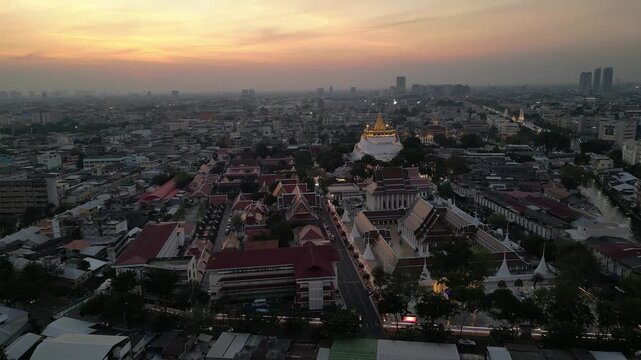 Aerial view of Wat Saket temple and the historic urban landscape under a golden sunset sky in Bangkok, Bangkok, Thailand.