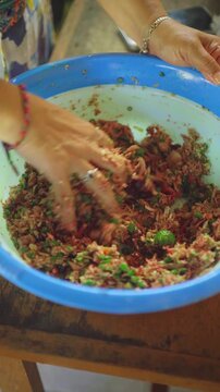 Woman's hand is mixing lawar, a traditional balinese food made from chopped meat mix with balinese spice, part of Galungan ceremony. 4K Vertical footage