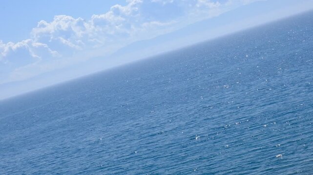 Majestic sea, horizon is oddly tilted, breaks the usual sense of balance. This compositional quirk transforms the ordinary seascape into something surreal, imbuing it with an alien, dreamlike quality.