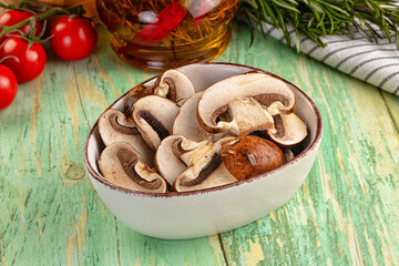 Fototapeta premium Sliced mushrooms in ceramic bowl with tomatoes and rosemary on rustic green wooden table