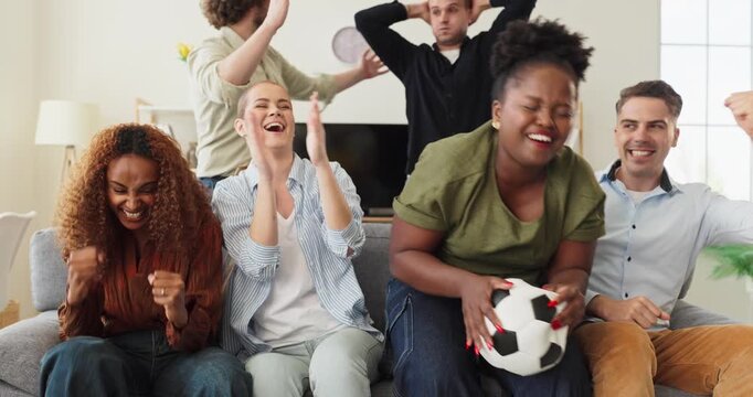 Friends fans watching soccer on tv cheering. Diverse group celebrates a goal at home. Great for sports ads, media and streaming promos worldwide. Clear concept of unity and celebration.