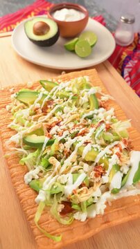 Top view of chicharron prepared with lettuce, shredded chicken, sour cream, cheese and red sauce, traditional Mexican cuisine and street food