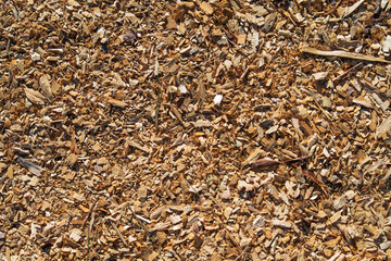 Fototapeta premium High angle close up view of brown wood chips used as organic mulch for gardening or biomass fuel. This natural texture background shows shredded timber pieces for landscaping.