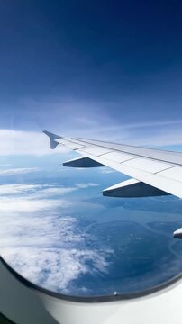airplane wing flying high above a river delta and sea coast seen through window
