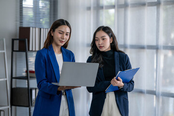 Obraz premium Businesswomen collaborating on laptop, discussing project in office
