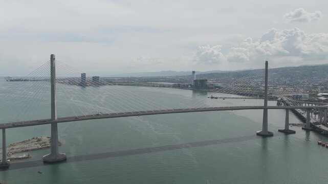 Aerial view of the Cebu-Cordova Link Expressway cable-stayed bridge spanning the Mactan Channel with the city skyline in the background in Cebu City, Central Visayas, Philippines.