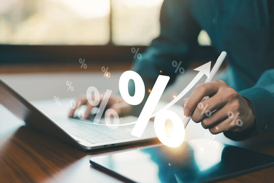 Interest rate increase concept with percentage symbols and upward over digital devices. Business professional analyzing investment returns, financial growth, savings performance, fintech innovation
