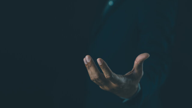 A hand reaches out from darkness, illuminated by soft light, symbolizing help, hope, or connection in a mysterious, minimalistic setting.