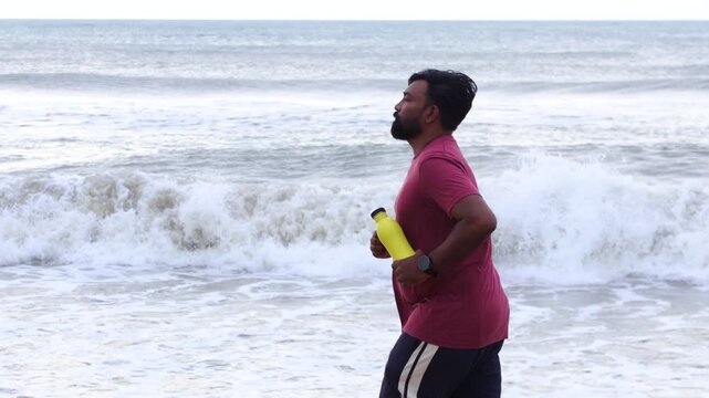 Bearded Man Jogging on Beach with Yellow Water Bottle for Summer Fitness and Hydration Lifestyle