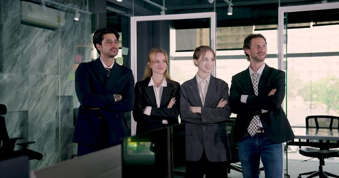Confident multicultural team of adult professionals standing in modern corporate office showing unity strength leadership and business cooperation in startup company environment