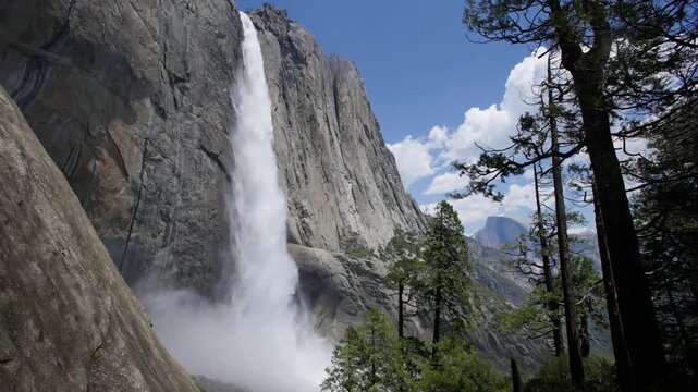 Upper Yosemite Falls flowing strongly with Half Dome in the distance in Yosemite National Park, California.