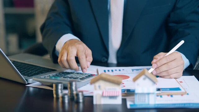 Businessman analyzing financial charts, counting coins, and using a calculator to evaluate asset sales and profits.