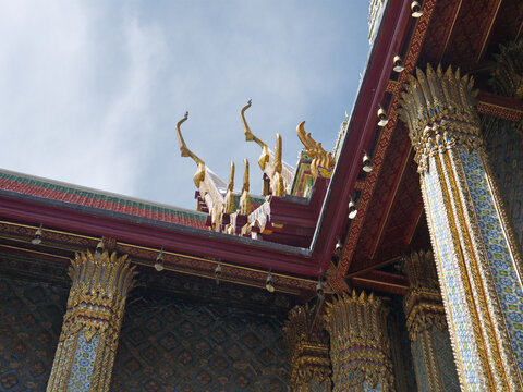 Close up of golden Chofa roof finials on multi-tiered temple roof, Bangkok