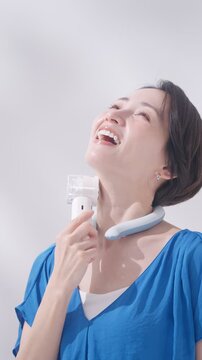夏にアイスリングとハンディ扇風機を使う女性