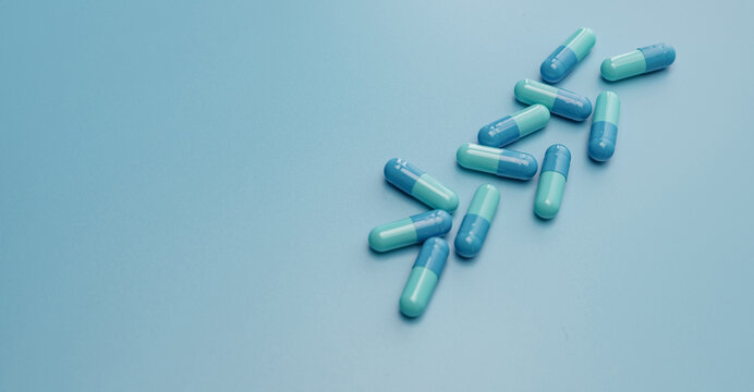 Blue capsule pills on blue background. Online pharmacy banner. Group of capsule pills. Pharmaceutical industry. Drug development and new drug research for treatment emerging Infectious diseases.