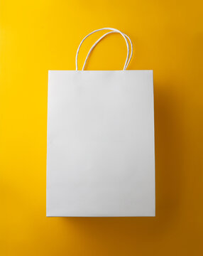 Blank White Paper Shopping Bag Mockup with Handles Isolated on Yellow Background