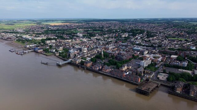 Aerial view of the urban landscape and historic waterfront along the River Thames with piers and rooftops under a soft sky in Gravesend, England, United Kingdom.