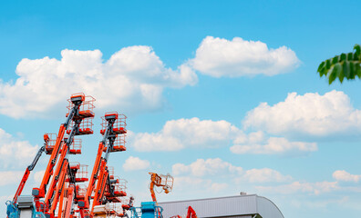 Articulated boom lift. Aerial platform lift. Telescopic boom lift against blue sky. Mobile crane parked at parking area for rent. Hydraulic boom lift at parking lot of crane dealership sale office. © Fahroni