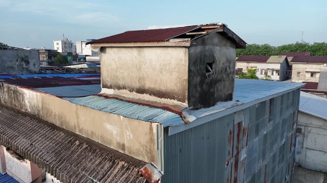 An aerial view captured by a drone shows a small swiftlet house with a rusty tin roof in an urban residential area.