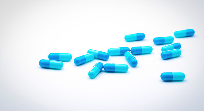 Blue antibiotic capsule pills spread on white background. Antibiotic drug resistance. Pharmaceutical industry. Healthcare and medicine concept. Health budget concept. Capsule manufacturing industry.
