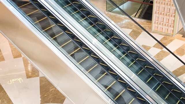 A modern parallel escalator in a luxury shopping mall looks deserted. The escalator moving smoothly parallel inside a modern shopping mall with elegant marble floors. Video transition, 4k, 60 fps