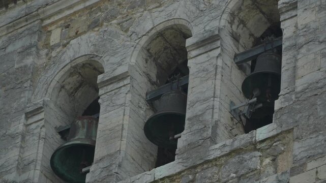 Historic church bell tower with stone arches and hanging bells in Luanco Spain