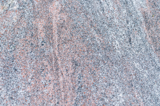 Close-up of polished red granite stone texture with natural grey and black veins. Indian aurora granite slab surface pattern backdrop for countertop or flooring design.Natural crystalline structure 