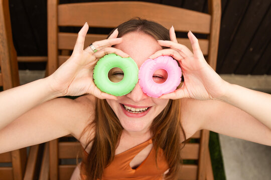 Smiling woman in swimsuit holding small green and pink swim ring