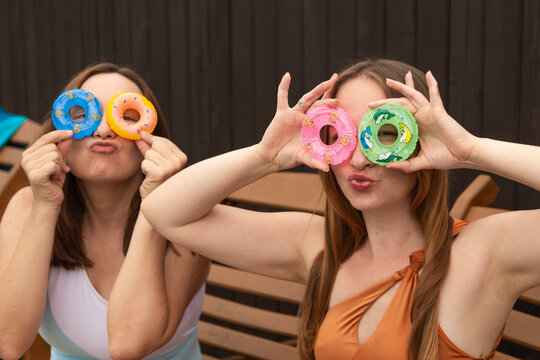 Two women in swimsuits making funny faces and holding small swim