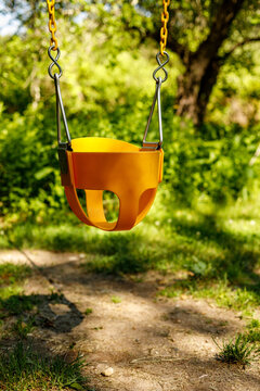 Yellow toddler swing hangs empty in a park