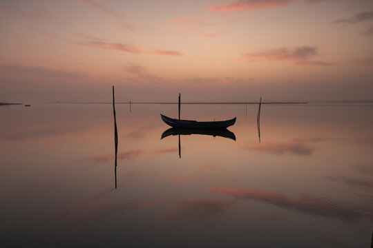 Serene boat floating on reflective water at dusk