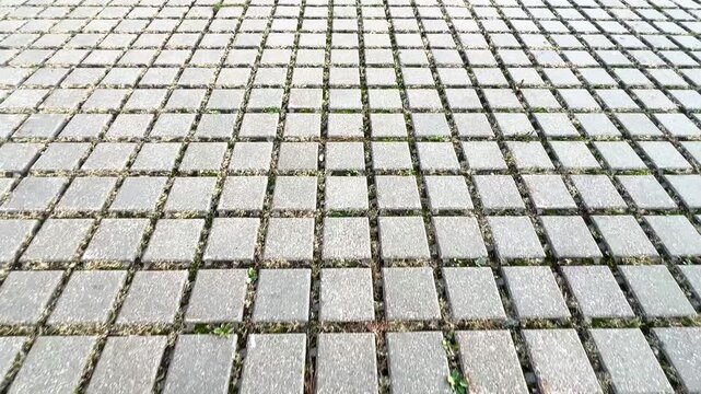 Textured ground surface with square pavers creating abstract geometric pattern