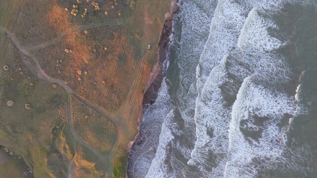 Orilla del mar con olas chocando contra acantilado, naturaleza costera vista cenital a&eacute;rea
