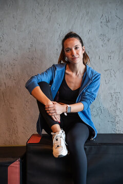 Woman in sportswear sitting on plyo box in gym