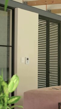 Vertical video: Panning camera centering black louvered doors in loft area, showing pink sofa