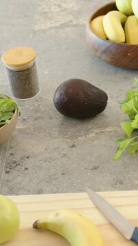 Vertical video: Recording cam capturing center avocado sitting on counter with knife, board to prep