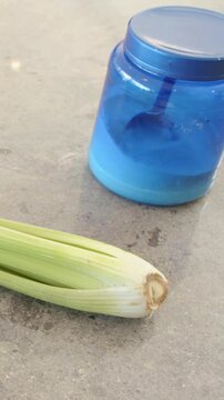 Vertical video: Panning shot revealing celery on counter, jar with spoon, apples for prep